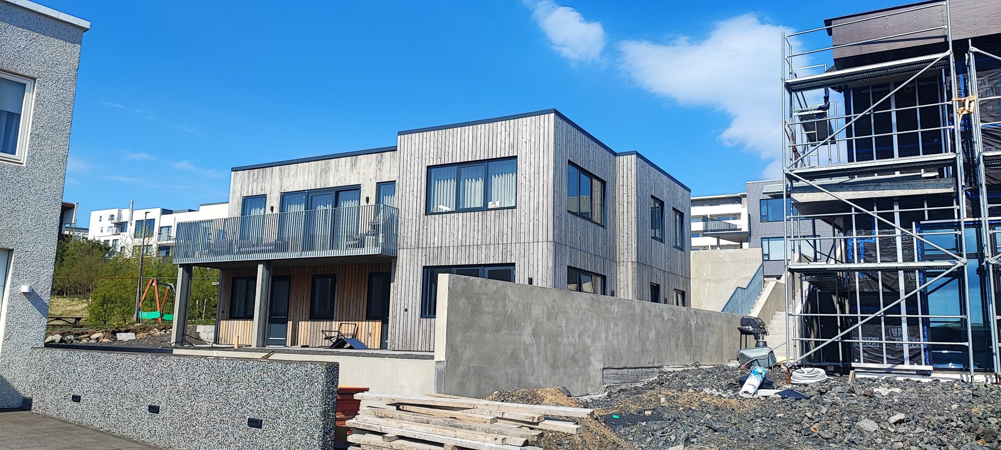 Raðhús með timburklæðningu og svölum á byggingarstað